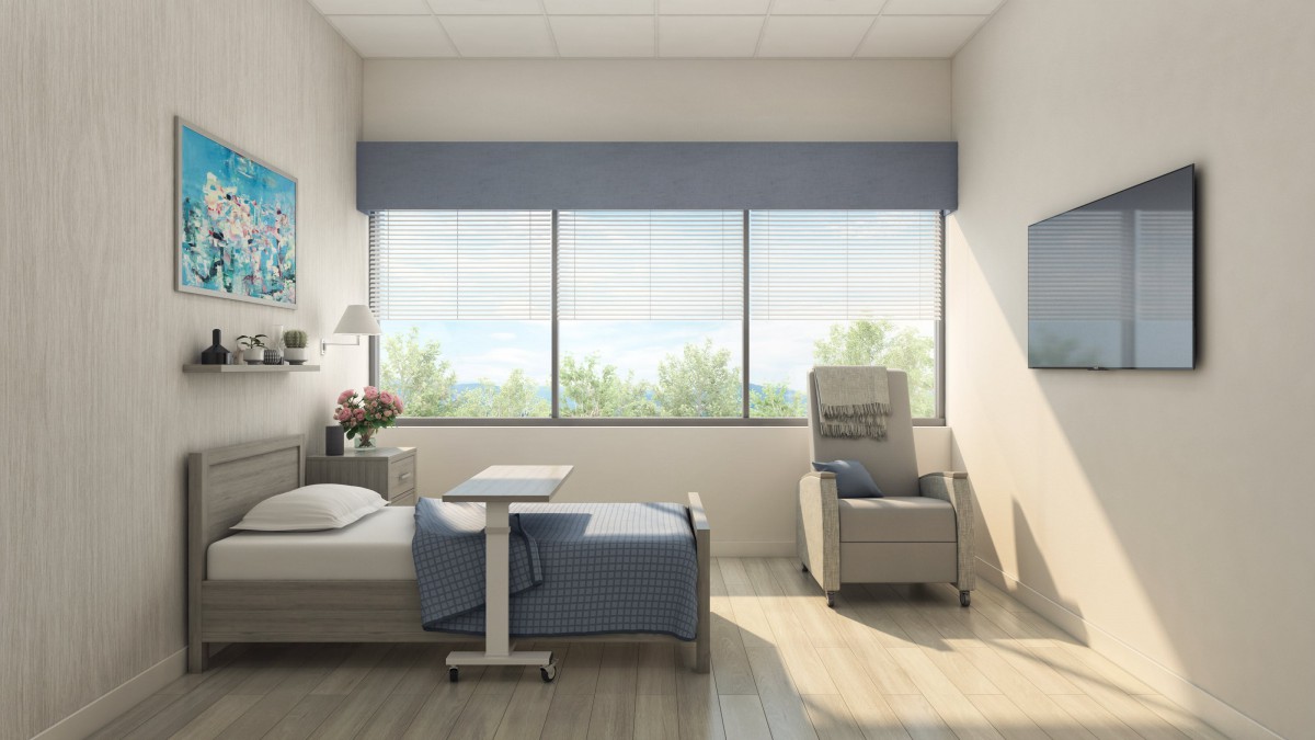 A bright and calming hospital room with a bed, chair, and large windows.