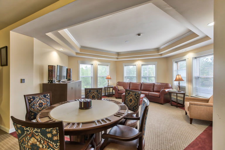 A spacious living room with a dining table, comfortable sofa, and large windows.