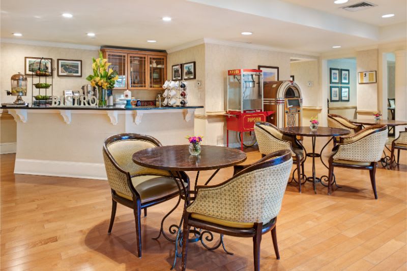 A charming cafe interior featuring a mix of retro decor with a popcorn machine and jukebox, elegant tables and chairs for seating.