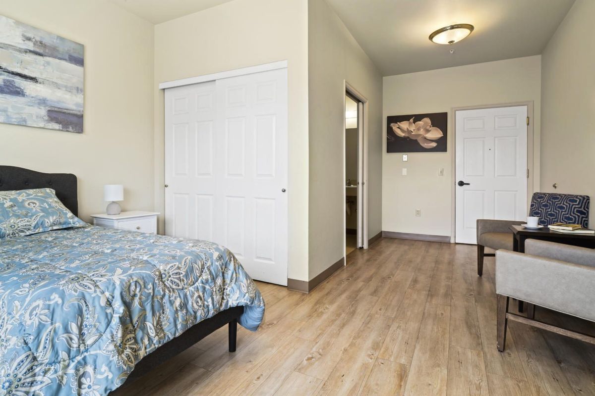 A spacious bedroom with wooden flooring and minimalist decor.