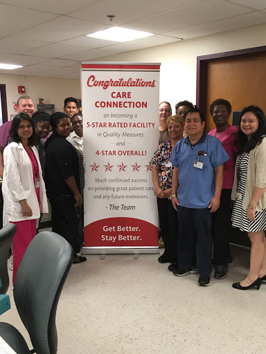 A dedicated healthcare team celebrating their achievements together in front of a congratulatory banner.