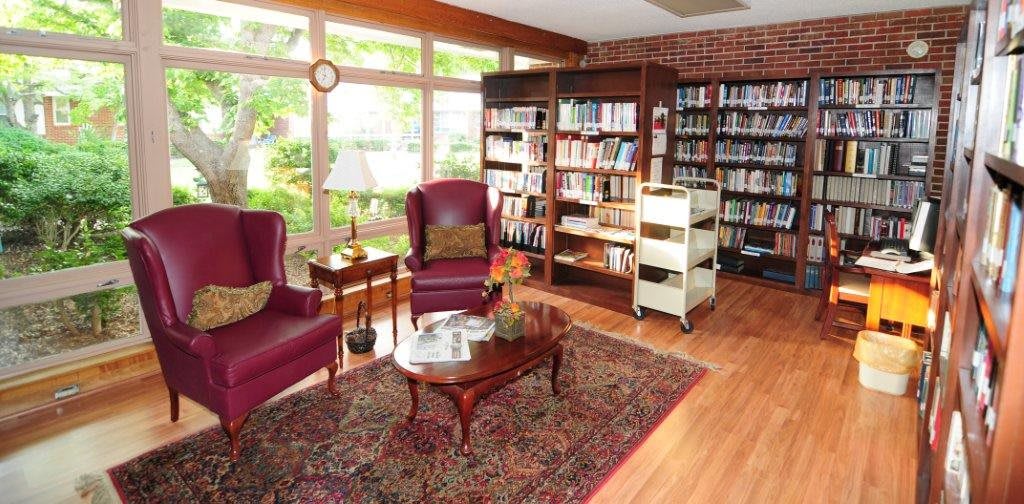 Cozy library reading area with armchairs, a coffee table, and bookshelves.
