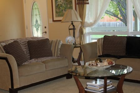 A cozy living room with a sofa, glass coffee table, and decorative elements.