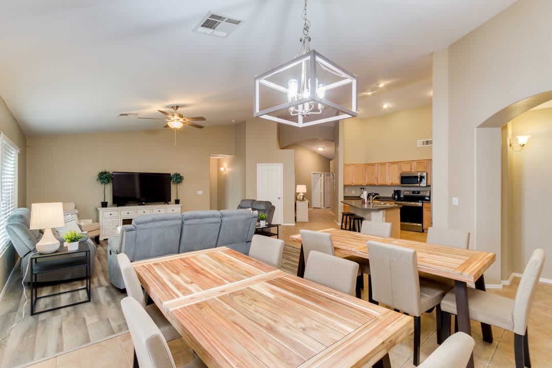 Modern open-plan living and dining area featuring a wooden dining table and contemporary lighting.