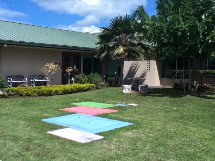 Canvas artworks drying on the lawn in a sunny backyard.