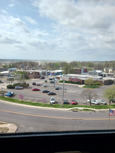 A panoramic view of a bustling suburban commercial area with cars parked in the lot under a cloudy sky.