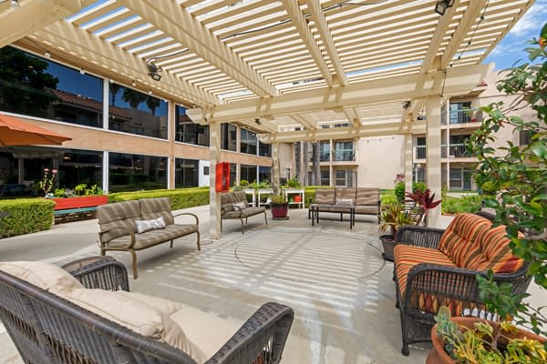 A modern outdoor patio with stylish seating under a pergola.