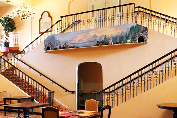 Elegant staircase with model train display and scenic artwork.