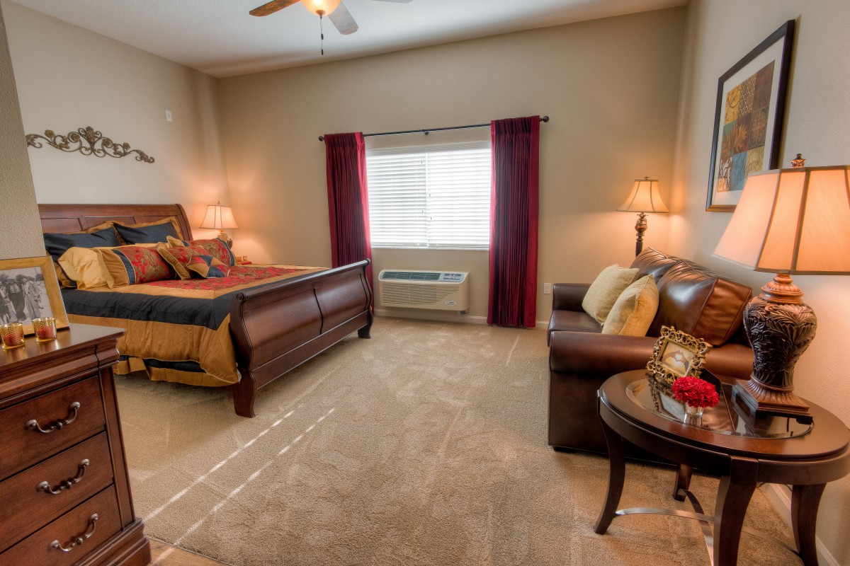 A cozy bedroom with a comfortable bed, sofa, and warm lighting.