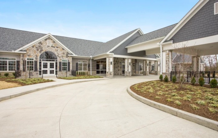 A modern building with a spacious driveway and landscaped surroundings.