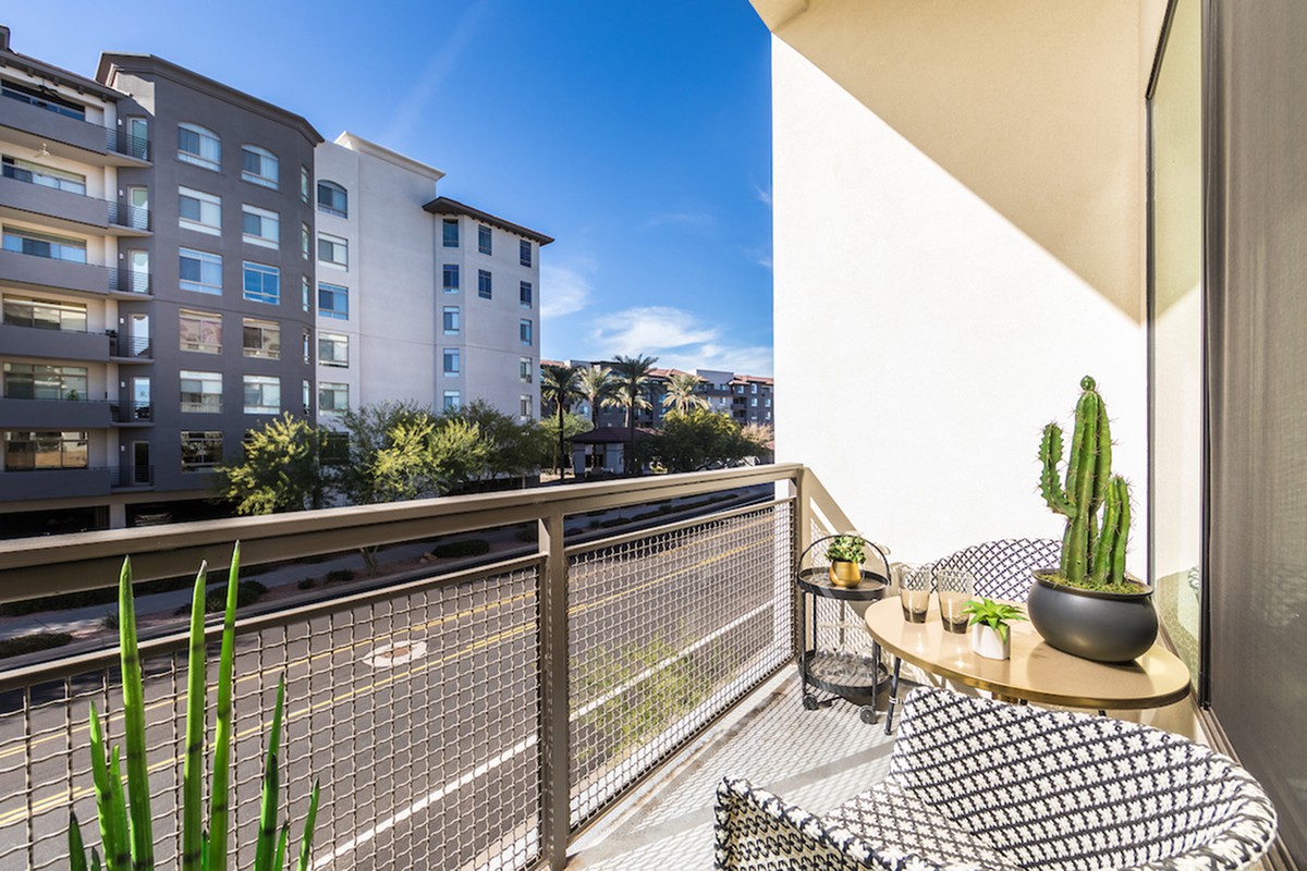 A modern balcony with outdoor seating and a view of city apartments.