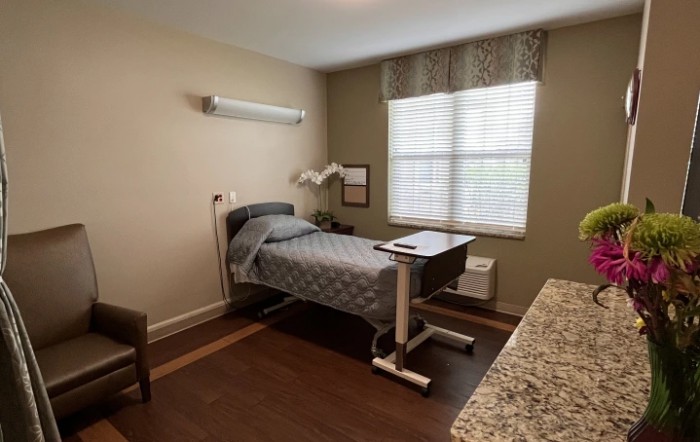 A simple hospital room with a single bed and medical equipment.