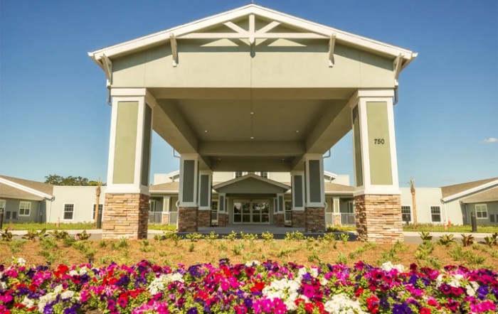 A covered building entrance with colorful flowers in the foreground.