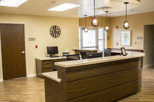 A modern reception area featuring a sleek desk, computer setup, and warm lighting.