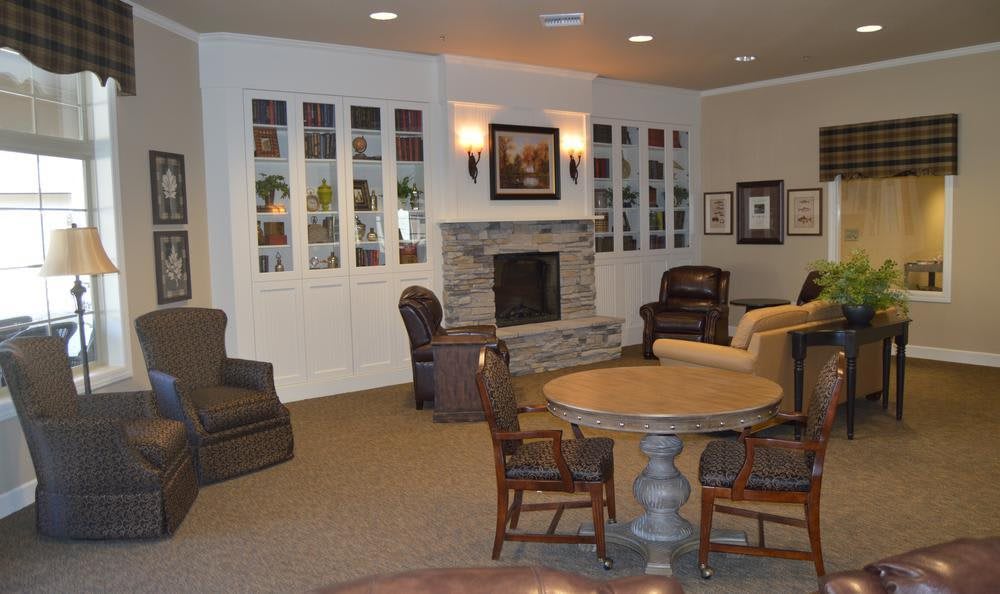 A cozy living room with a fireplace, surrounded by comfortable seating and bookshelves.