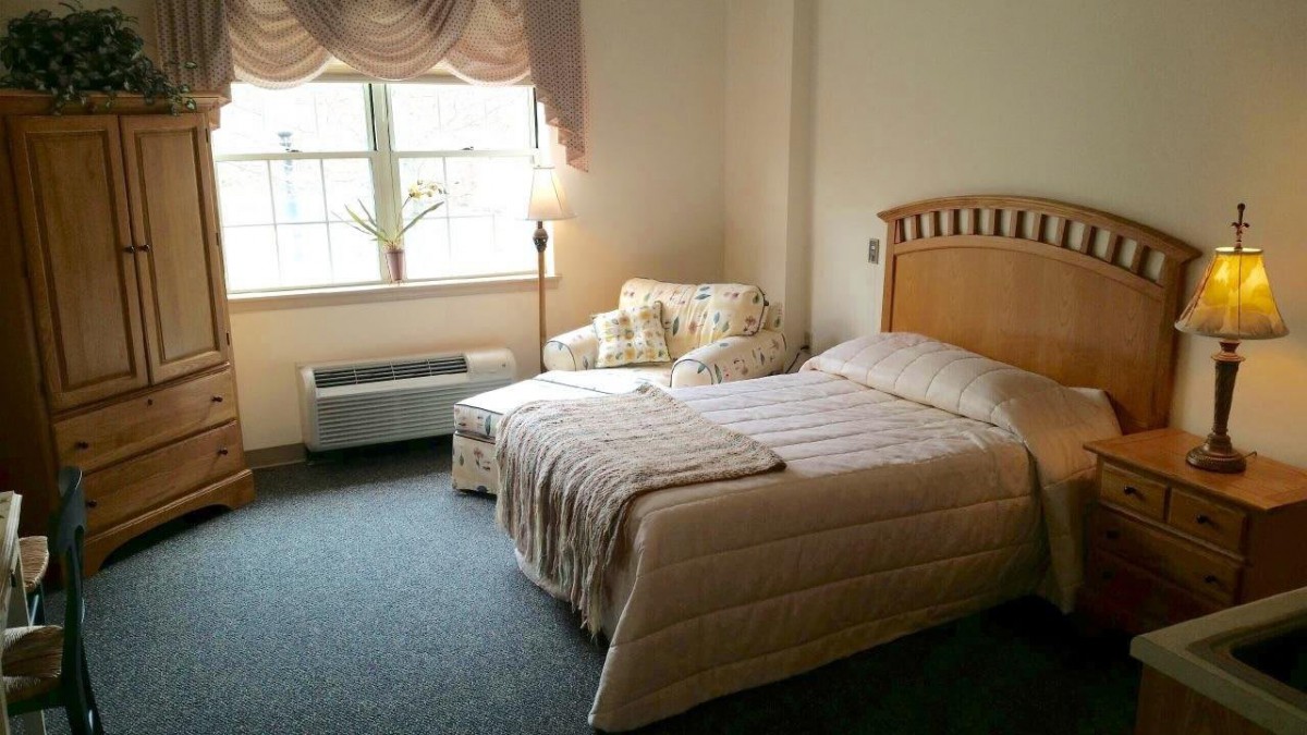 A cozy bedroom with a single bed, chair, and window providing natural light.