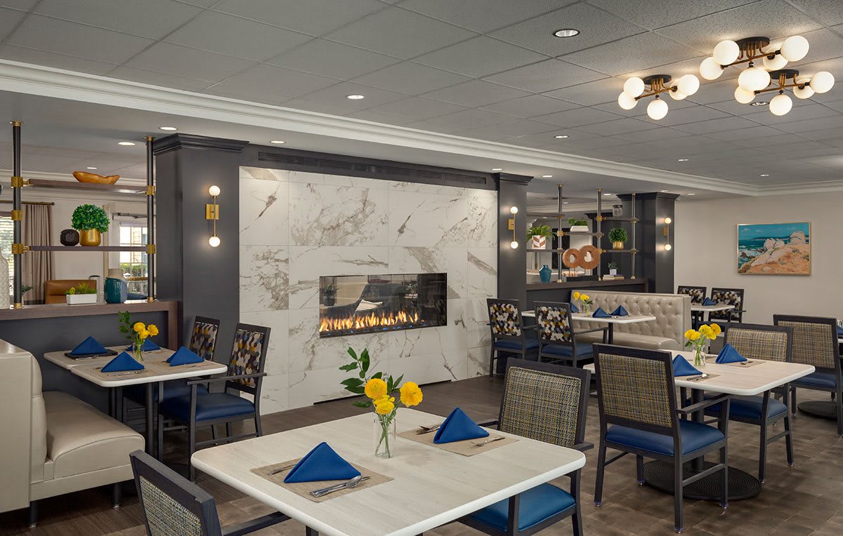 A modern dining area with neatly arranged tables and a central fireplace.