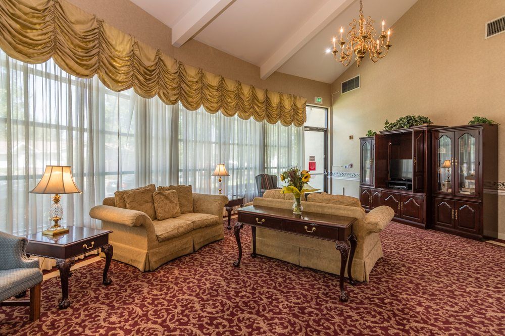 A spacious and elegantly decorated living room featuring plush sofas, a large carpet, and a chandelier.