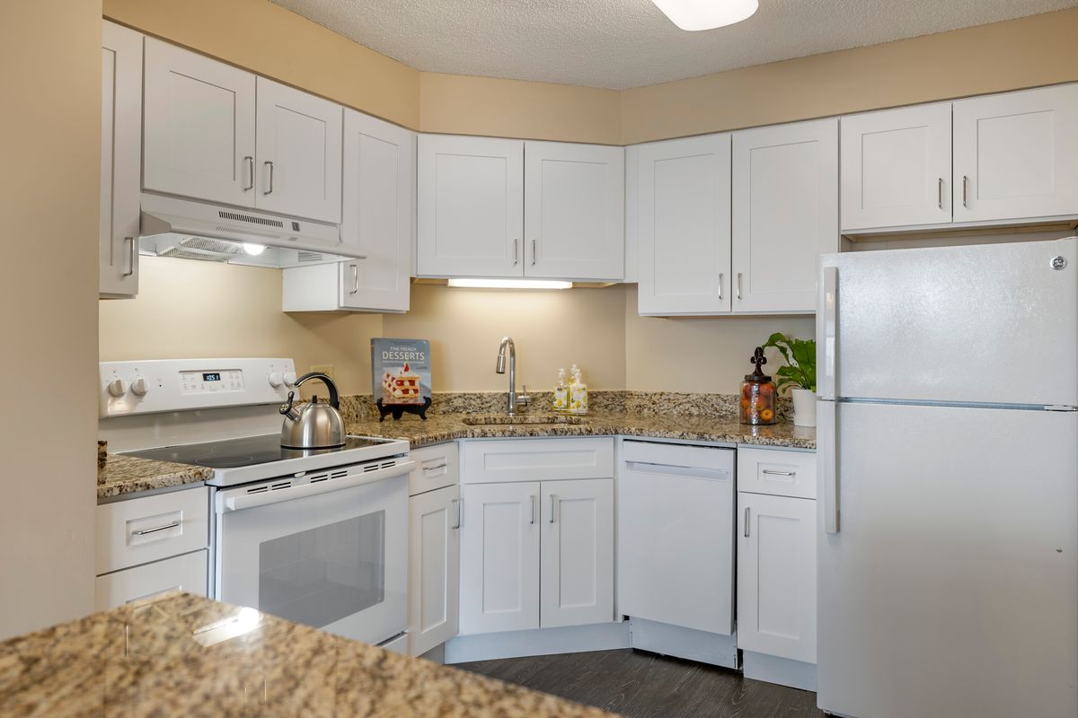 A modern kitchen with white cabinets and granite countertops.