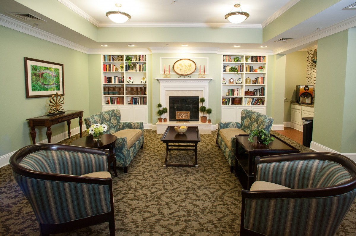 A cozy living room with comfortable seating and a fireplace, surrounded by bookshelves.