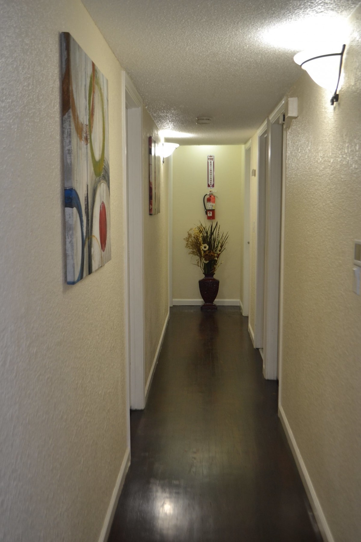 A narrow hallway with a decorative vase and a painting on the wall.