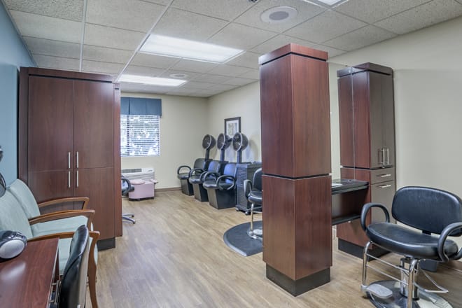 An interior view of a salon with chairs, hair dryers, and wood flooring.