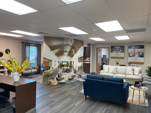 A modern office interior featuring a lounge area with stylish furniture and bright lighting, complemented by a decorative wall mural.