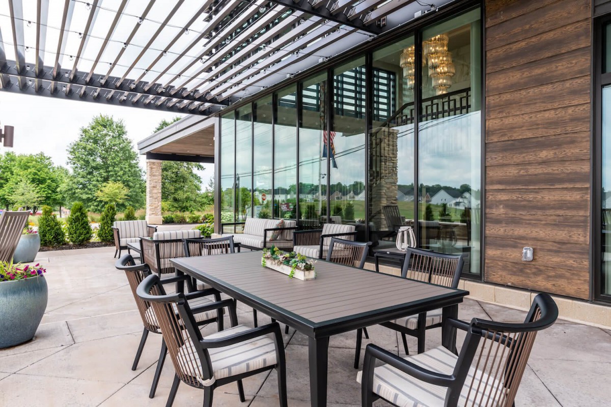 A modern outdoor patio with a dining table and chairs set under a pergola.