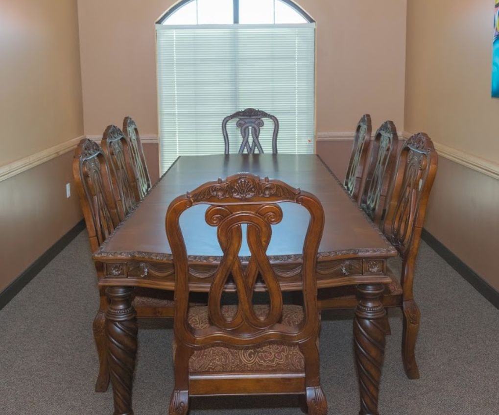 A classic wooden dining set with a table and six chairs in a well-lit room.