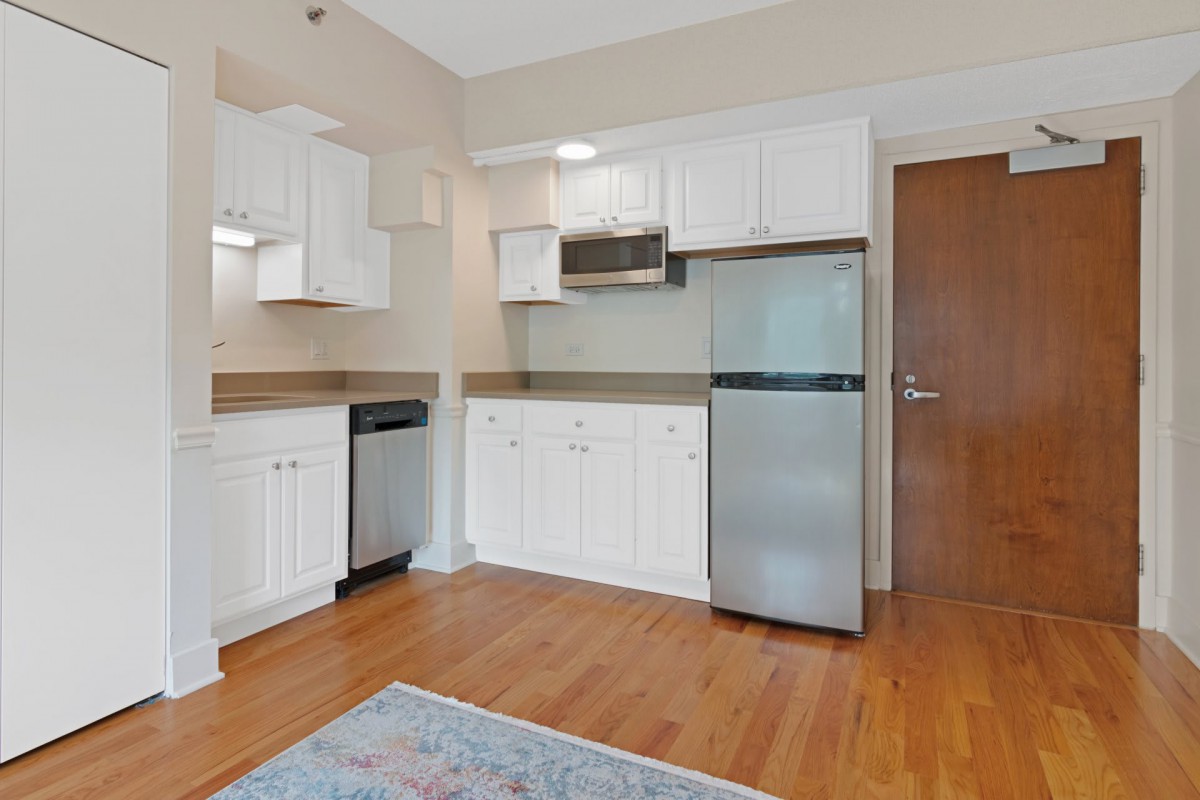 A compact kitchen with white cabinets and stainless steel appliances.