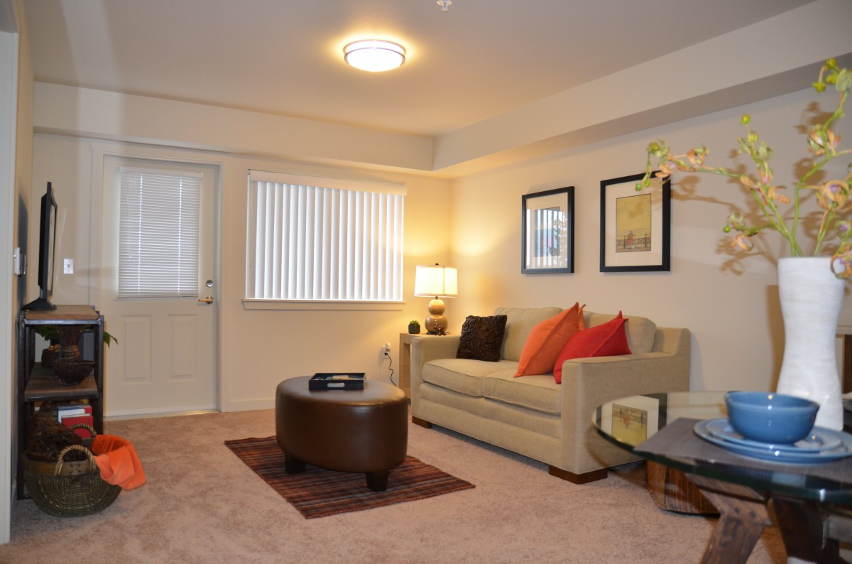 A cozy living room with a sofa, colorful pillows, and framed artwork on the walls.