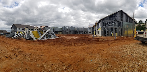 A panoramic view of a construction site with framed houses under a cloudy sky.