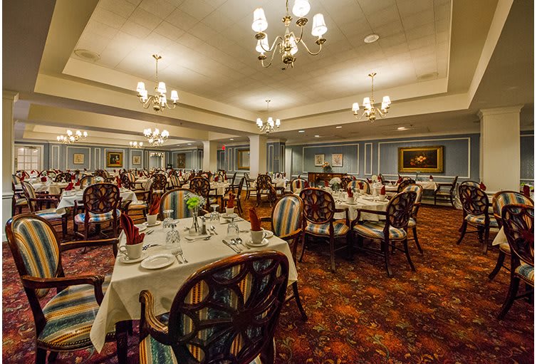 A spacious and elegantly decorated dining room with set tables and ornate chandeliers.