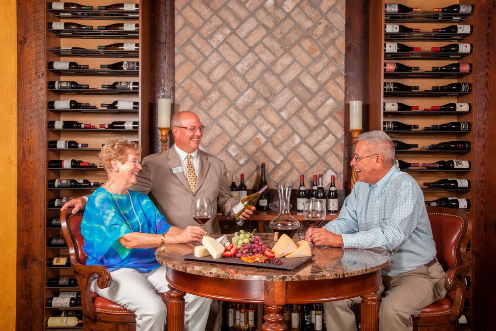 Three people enjoying a wine tasting in a cozy wine cellar setting.
