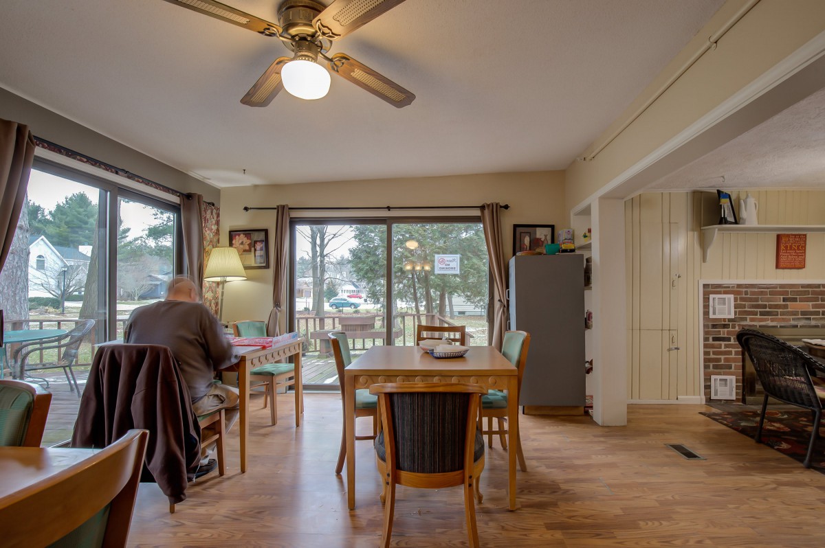 A cozy dining room with a wooden table and chairs, featuring large windows that let in natural light.