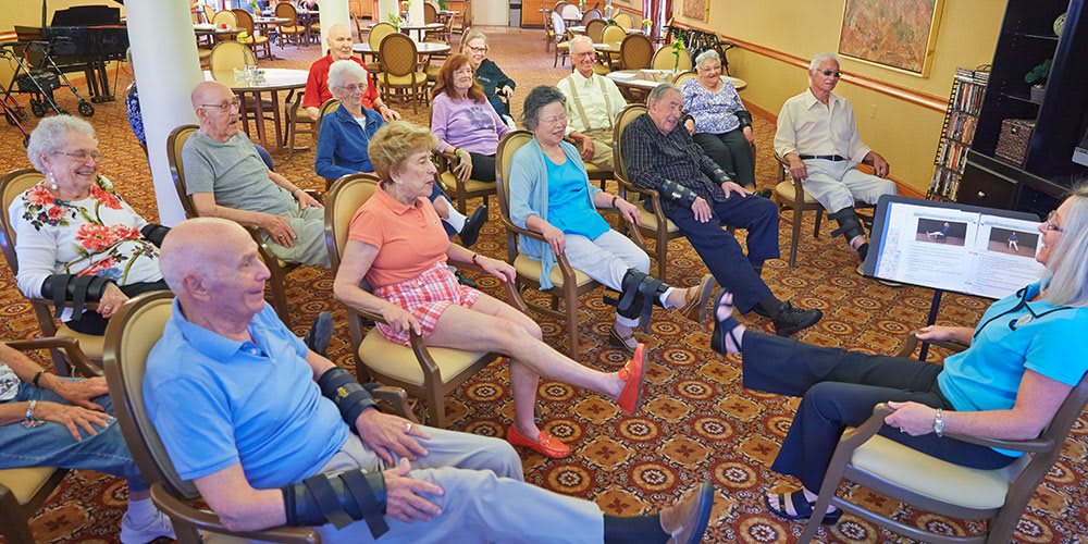 A group of senior citizens participating in a seated exercise session at a community center.