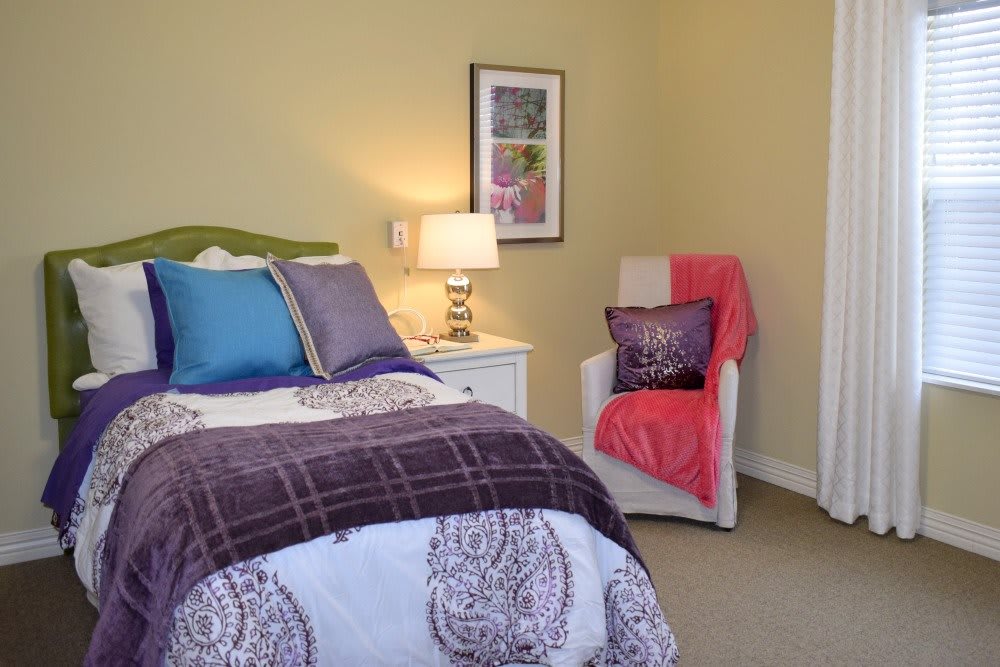 A cozy bedroom with colorful bedding and a well-lit lamp on the nightstand.