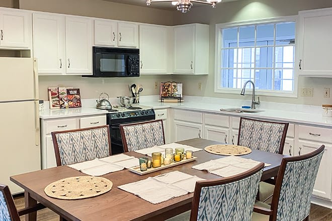 A modern kitchen with a dining area featuring white cabinets and sleek appliances.