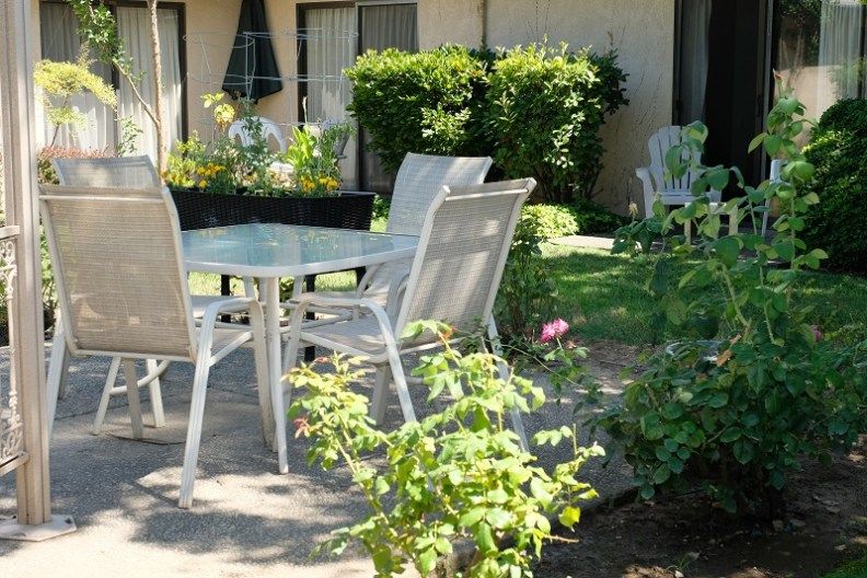 A tranquil garden setting with patio furniture surrounded by lush greenery.