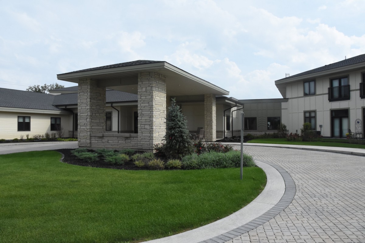 A modern building with a circular driveway and landscaped greenery.