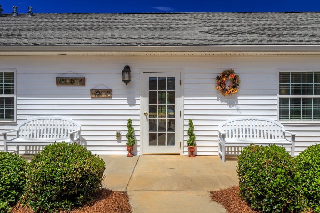 A welcoming house entrance with a wreath on the door and benches on either side.
