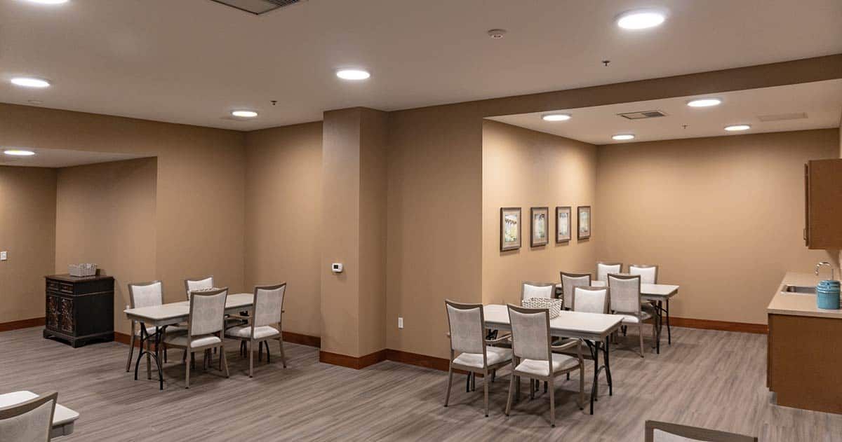 An empty conference room with tables and chairs arranged neatly, adorned with wall art.