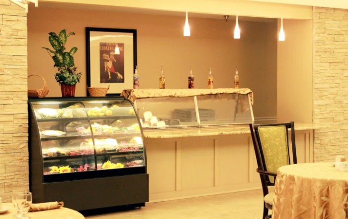 An inviting bakery with a well-lit cake display and comfortable seating area.