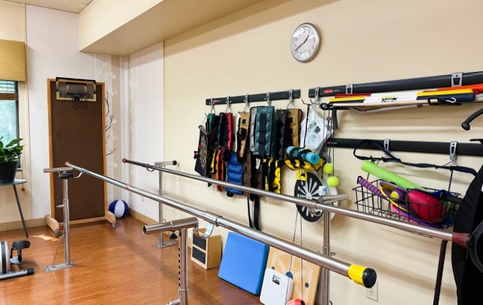 A rehabilitation room equipped with exercise tools, including parallel bars and various therapy equipment.