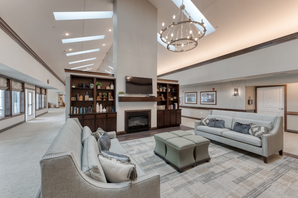 A modern living room with elegant furniture, a central fireplace, and natural light from skylights.