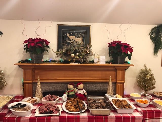 A festive holiday buffet with a variety of dishes set on a table adorned with Christmas decorations and poinsettias.