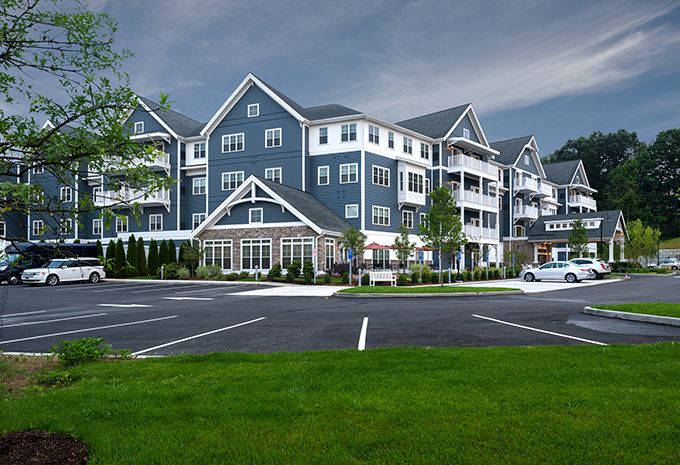 A modern residential apartment complex with a large parking area and well-maintained landscaping.