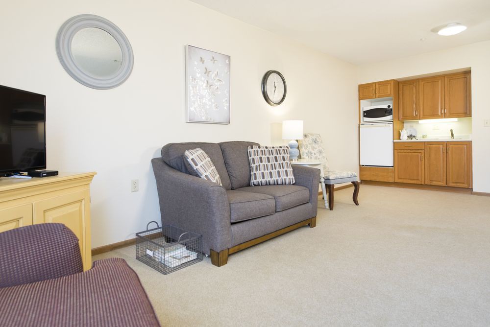 A cozy living room with a gray sofa, decorative pillows, and a wall clock.