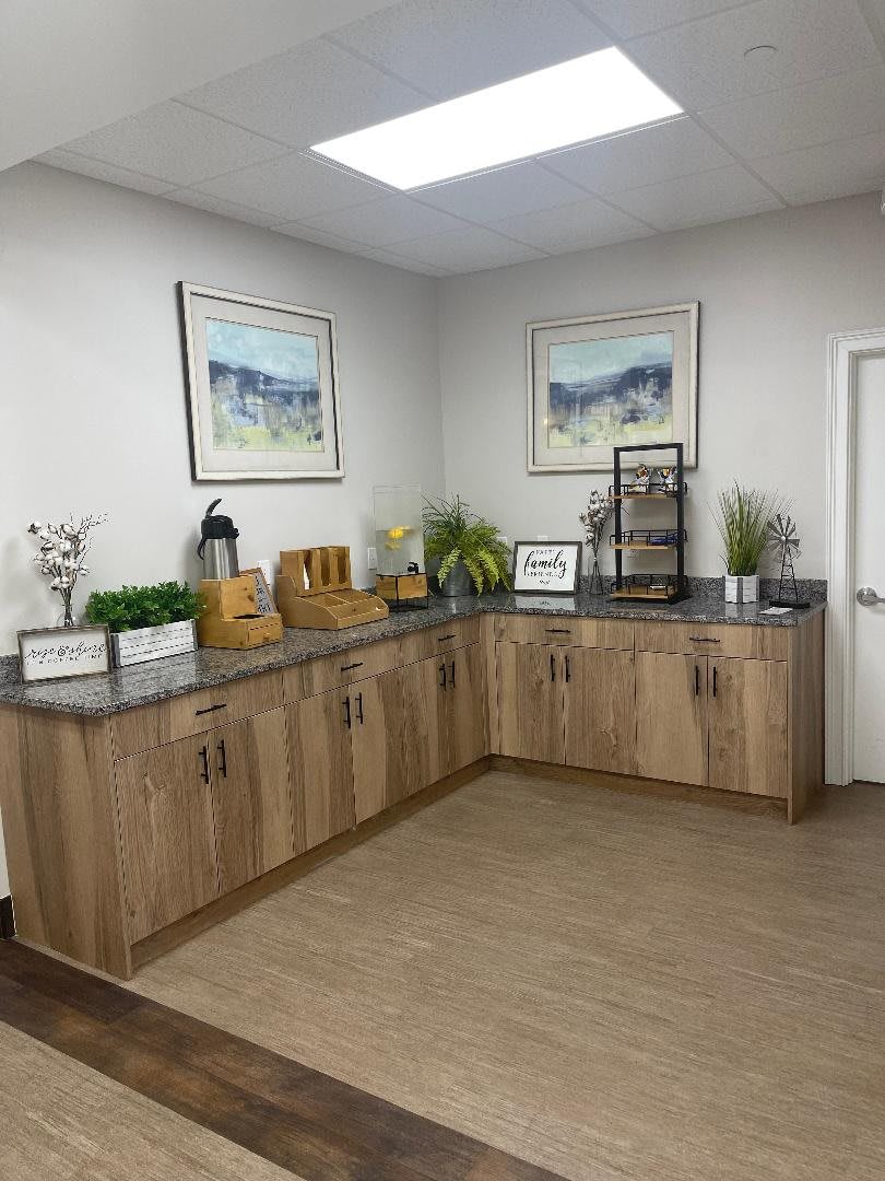 A neatly organized office space featuring wooden cabinetry, decorative plants, and artwork on the walls.