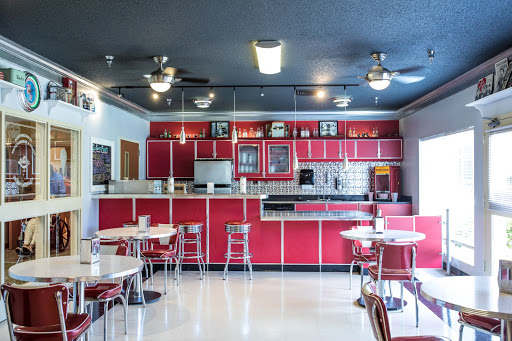 A vibrant retro diner kitchen with striking red cabinetry and classic furniture.